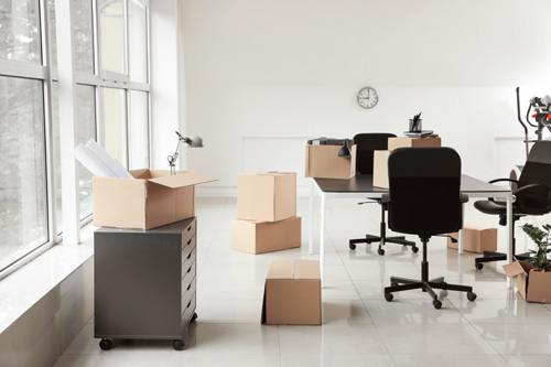 Cardboard-boxes-with-belongings-and-furniture-in-new-office-on-moving-day.jpg