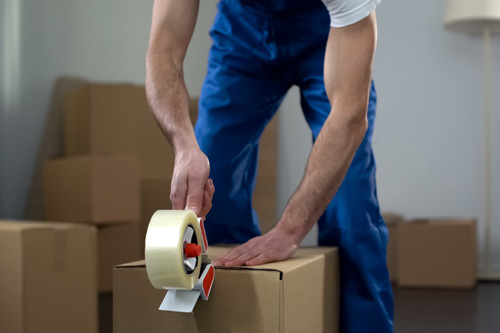 Moving-company-worker-packing-cardboard-boxes.jpg